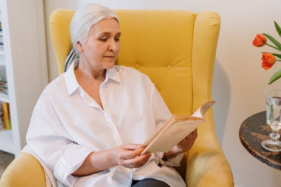 senior lisant dans son fauteuil de chambre